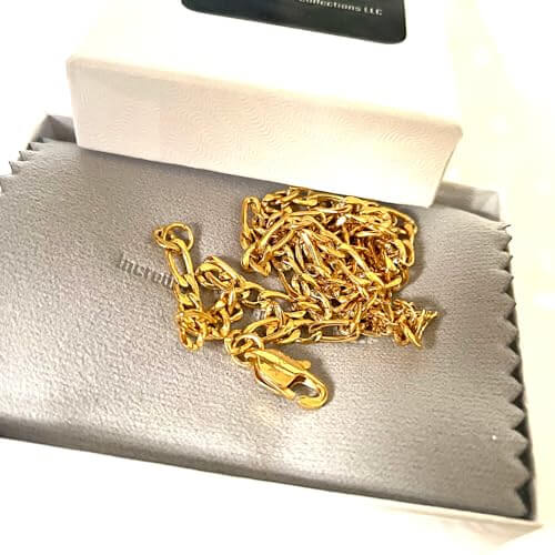24K gold filled Figaro chain necklace displayed in a jewelry box with storage cloth.