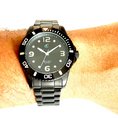 Load image into Gallery viewer, Black watch with a black face on a wrist against a white background
