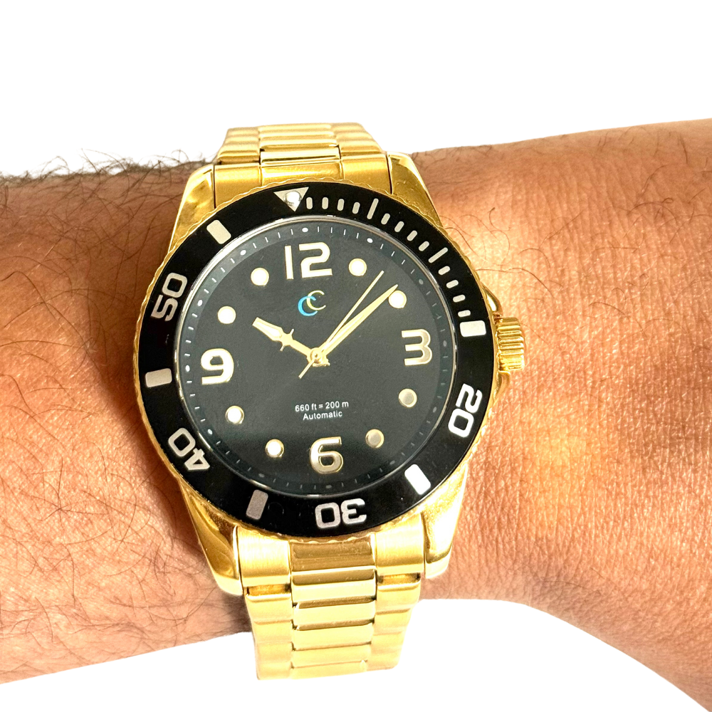 Gold wristwatch with black dial on a wrist against a white background