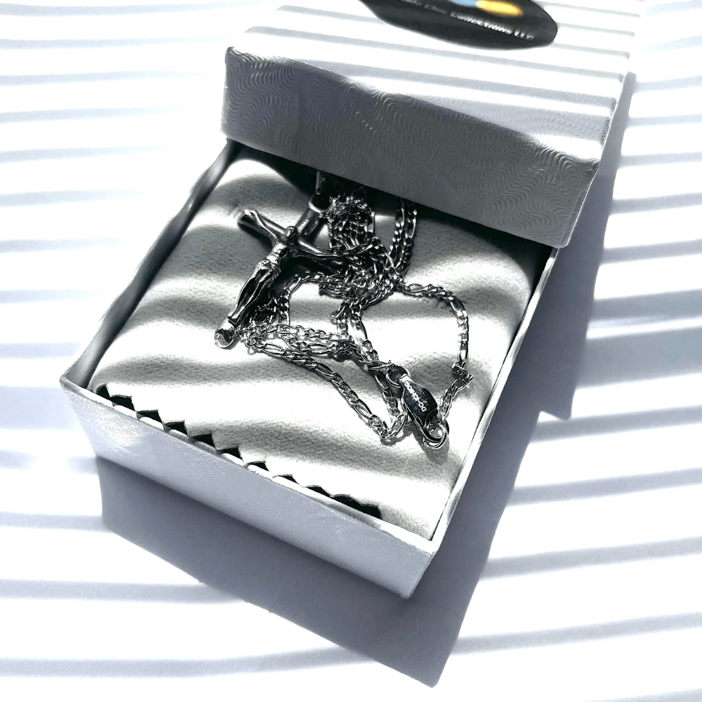 14k white gold crucifix necklace resting in elegant gift box with soft fabric lining and striped shadows.