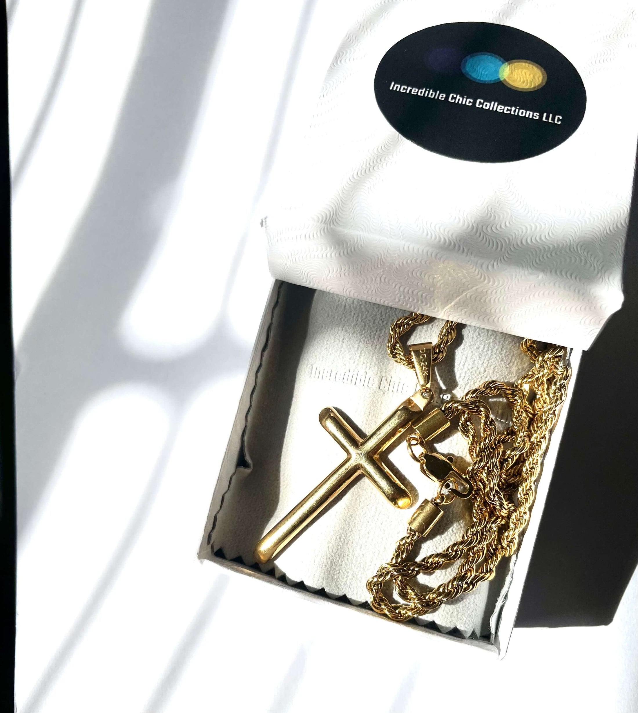 24K gold rope chain cross pendant in a box by Incredible Chic Collections, showcasing luxury and craftsmanship.