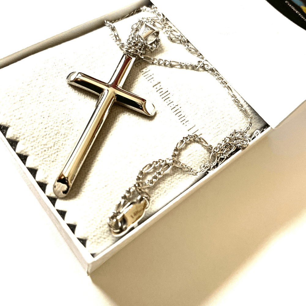 Silver cross pendant necklace presented in an elegant gift box, showcasing its gleaming shine and intricate chain design.