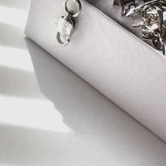 Close-up of a white embossed jewelry box with a silver clasp, ideal for storing necklaces and accessories.