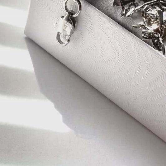 Close-up of a white embossed jewelry box with a silver clasp, ideal for storing necklaces and accessories.