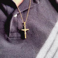 Load and play video in Gallery viewer, Close-up of a 24k yellow gold filled crucifix necklace worn on a black polo shirt, showcasing its intricate design.
