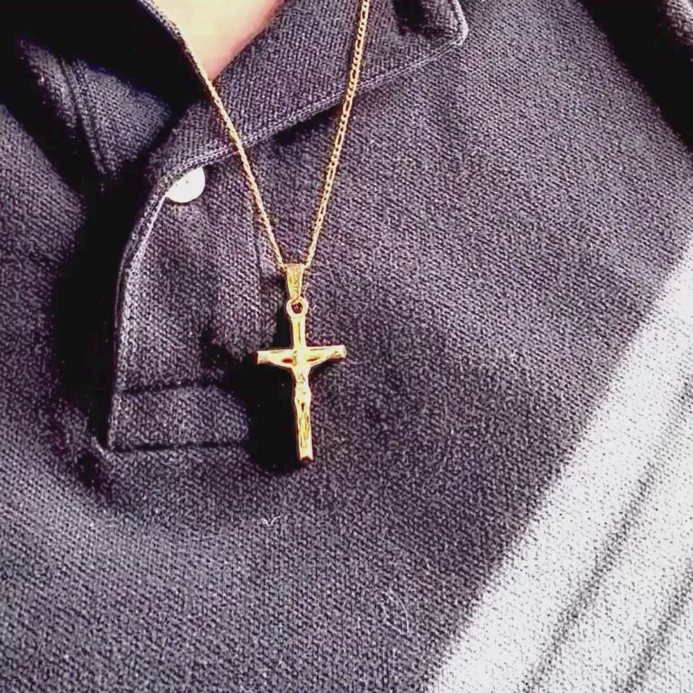 Close-up of a 24k yellow gold filled crucifix necklace worn on a black polo shirt, showcasing its intricate design.